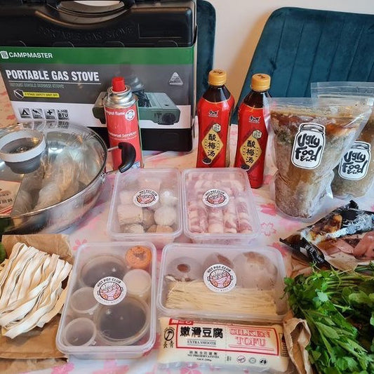 All the DIY Hot Pot Kit ingredients laid out on a table with a tablecloth.